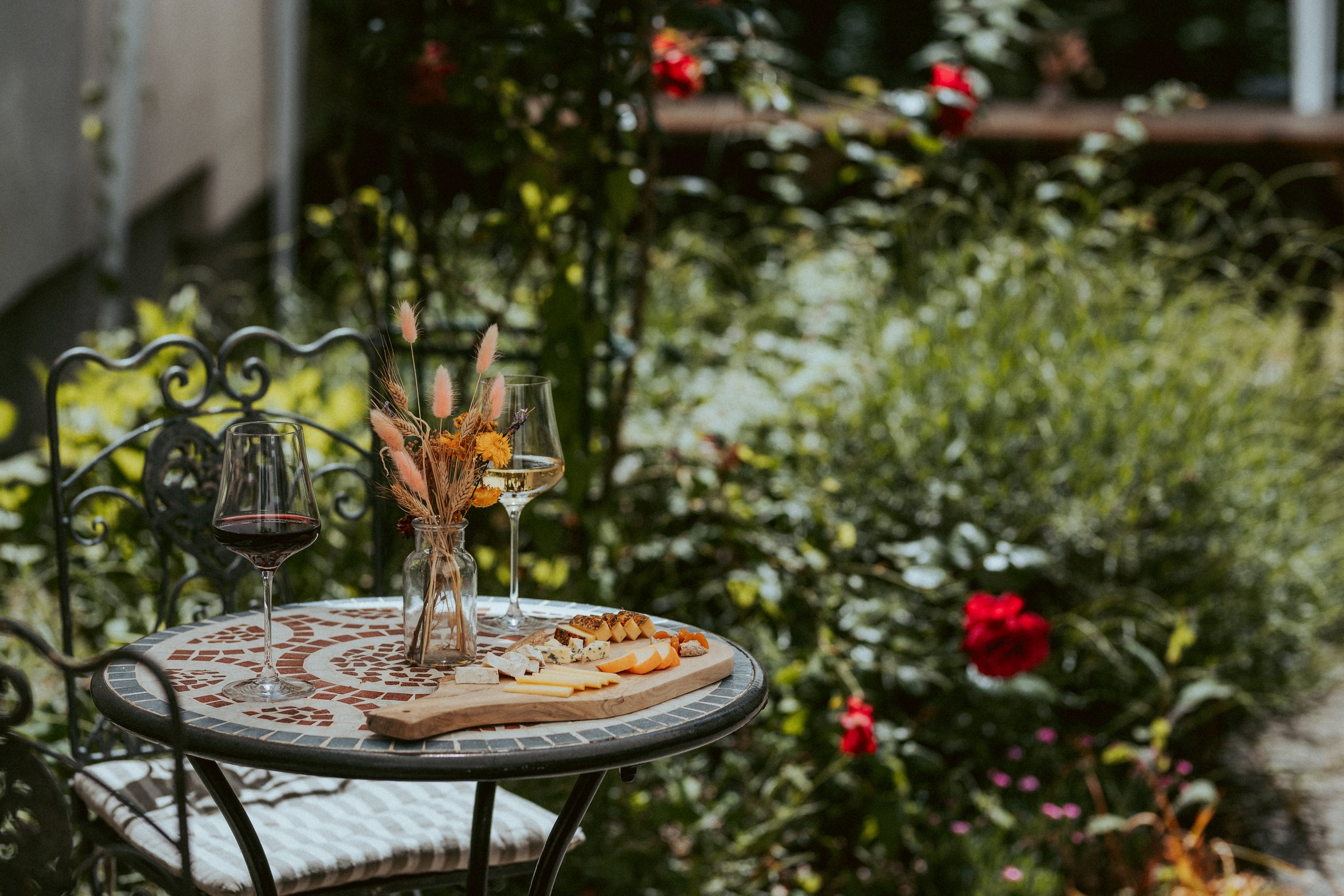 Kleiner Tisch im Garten mit Wein und Käse